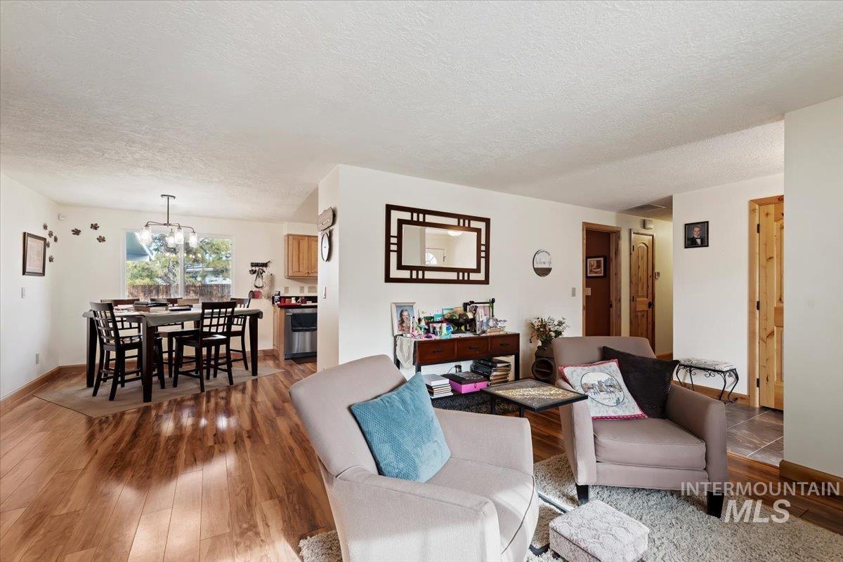 Living room featuring a textured ceiling, a chandelier, and wood finished floors