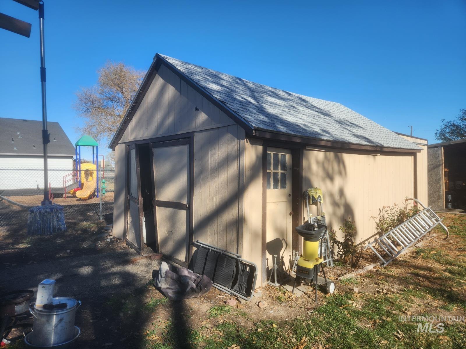 View of property exterior with roof with shingles and a shed