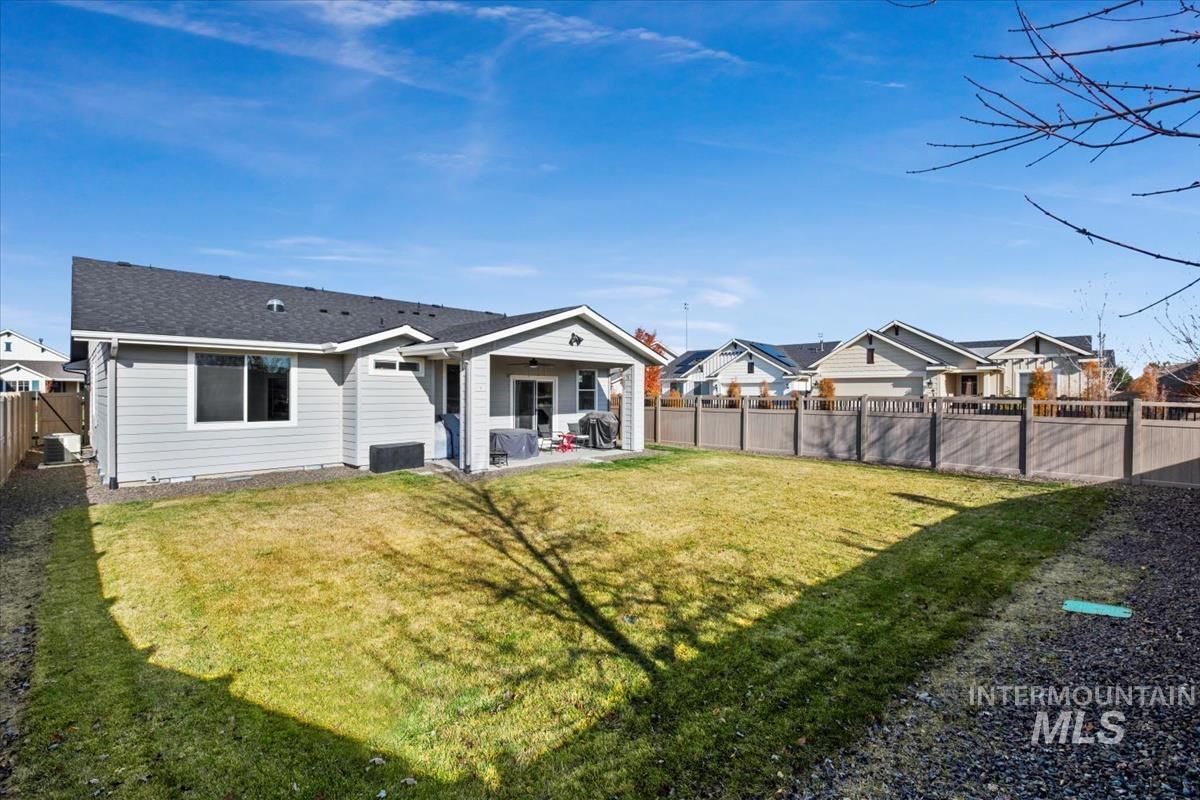 Back of house featuring a patio, a fenced backyard, a residential view, and a shingled roof