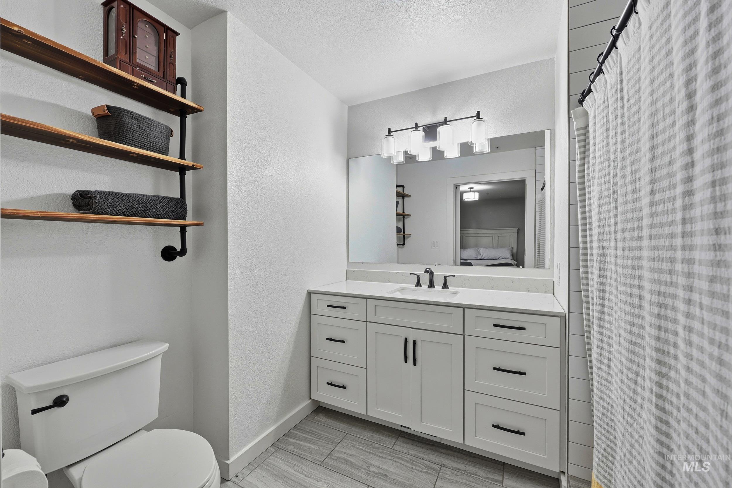 Ensuite bathroom featuring curtained shower, vanity, and a textured wall