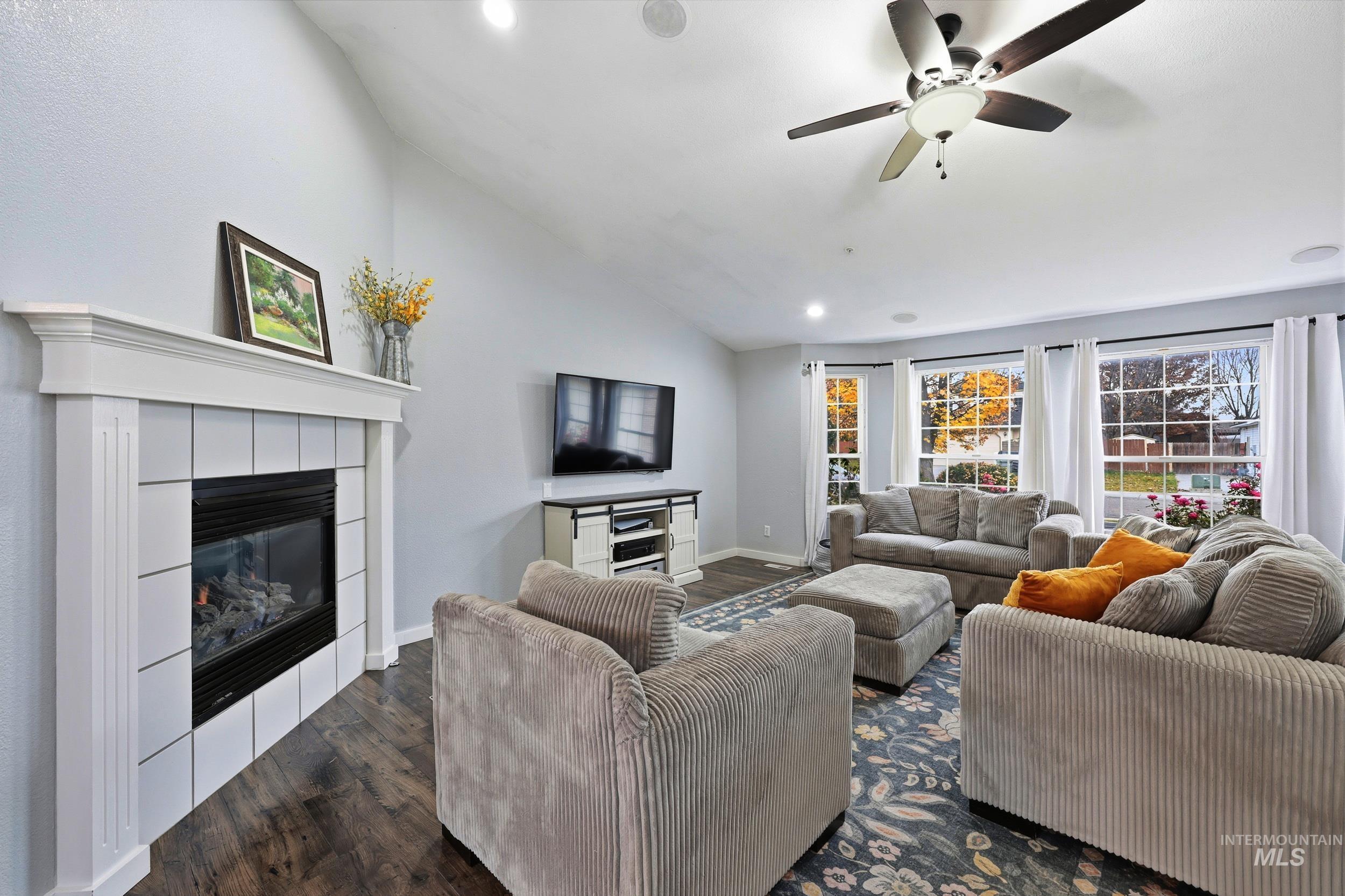 Living room with vaulted ceiling, dark wood-style flooring, a fireplace, recessed lighting, and ceiling fan