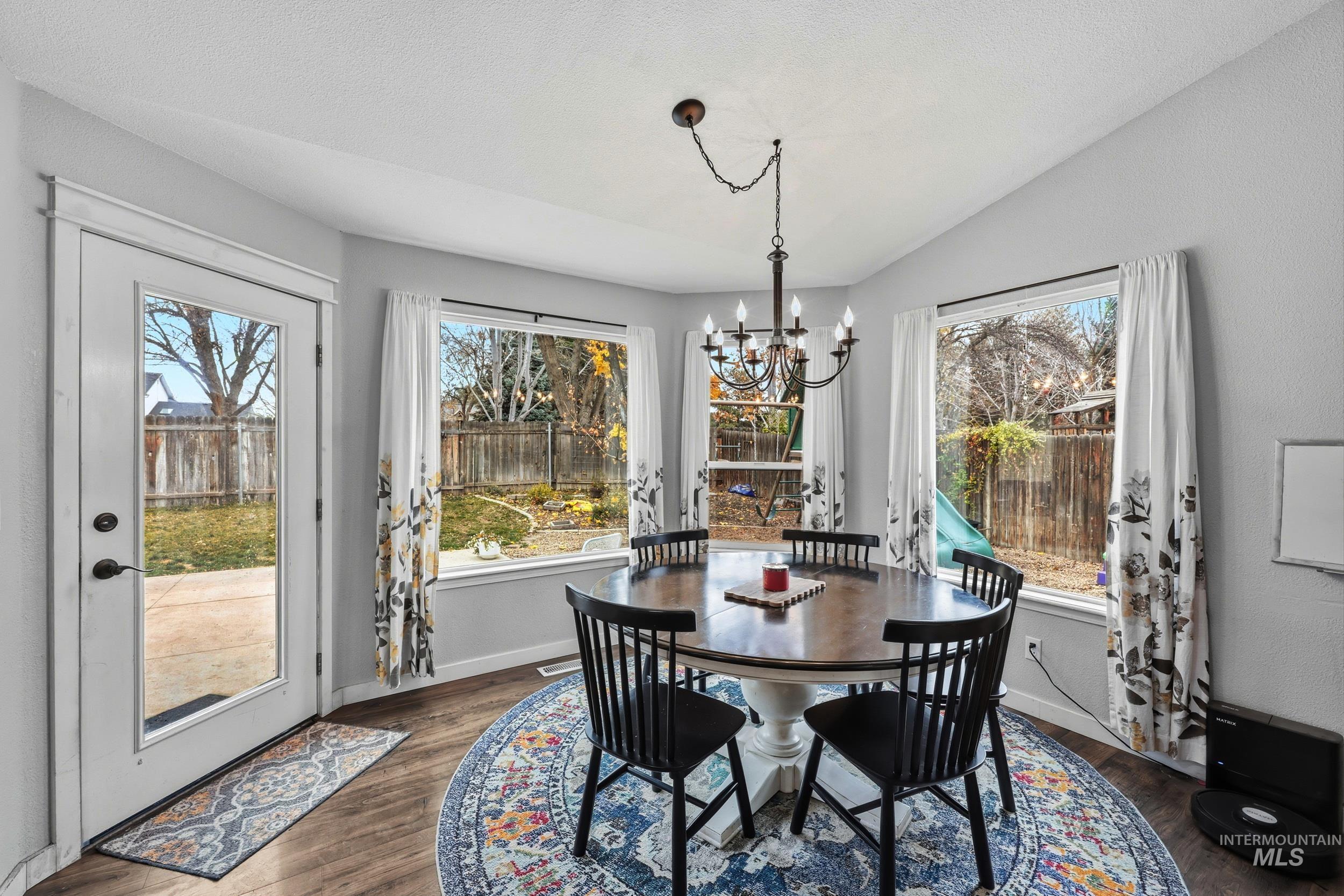 Dining area featuring dark wood-type flooring, a chandelier, and vaulted ceiling