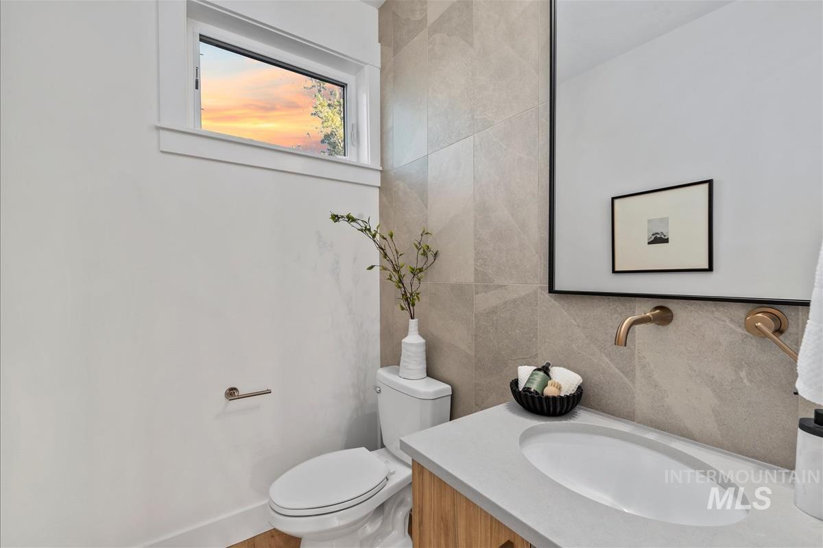 Half bath featuring vanity, tile walls, and tasteful backsplash