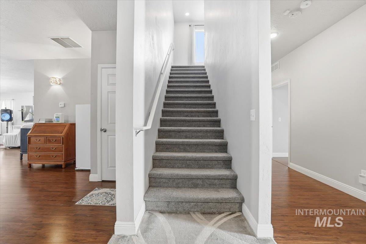 Staircase featuring wood finished floors and a textured ceiling