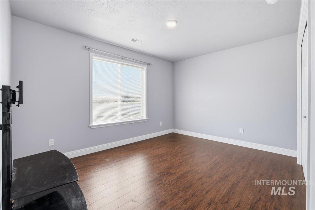 Unfurnished room featuring dark wood-type flooring and a textured ceiling