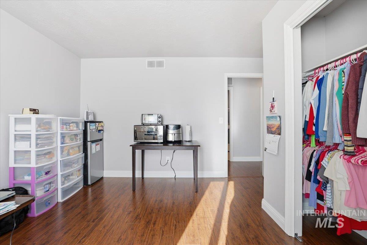 Bedroom featuring dark wood-type flooring, freestanding refrigerator, and a closet