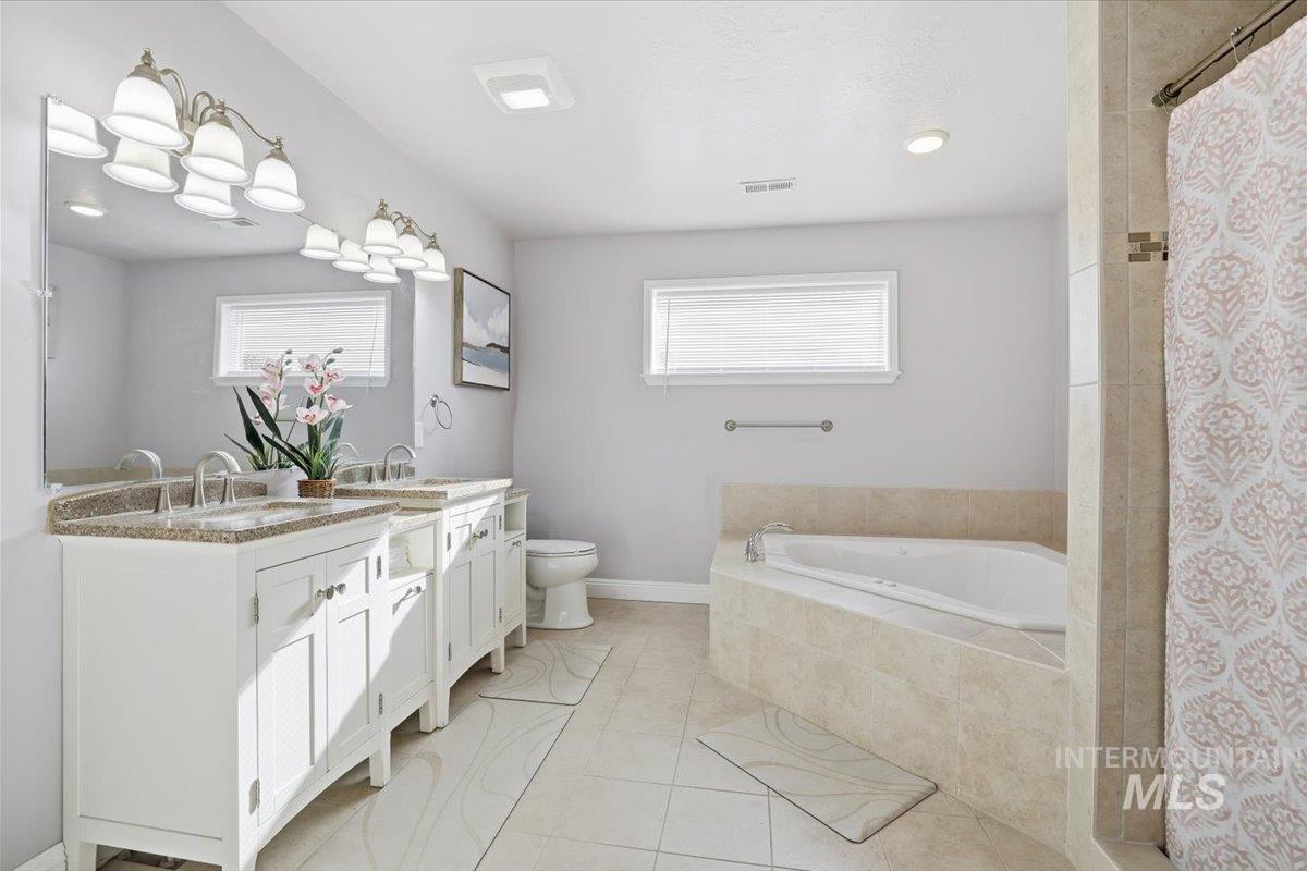 Bathroom featuring a garden tub, light tile patterned floors, double vanity, curtained shower, and recessed lighting