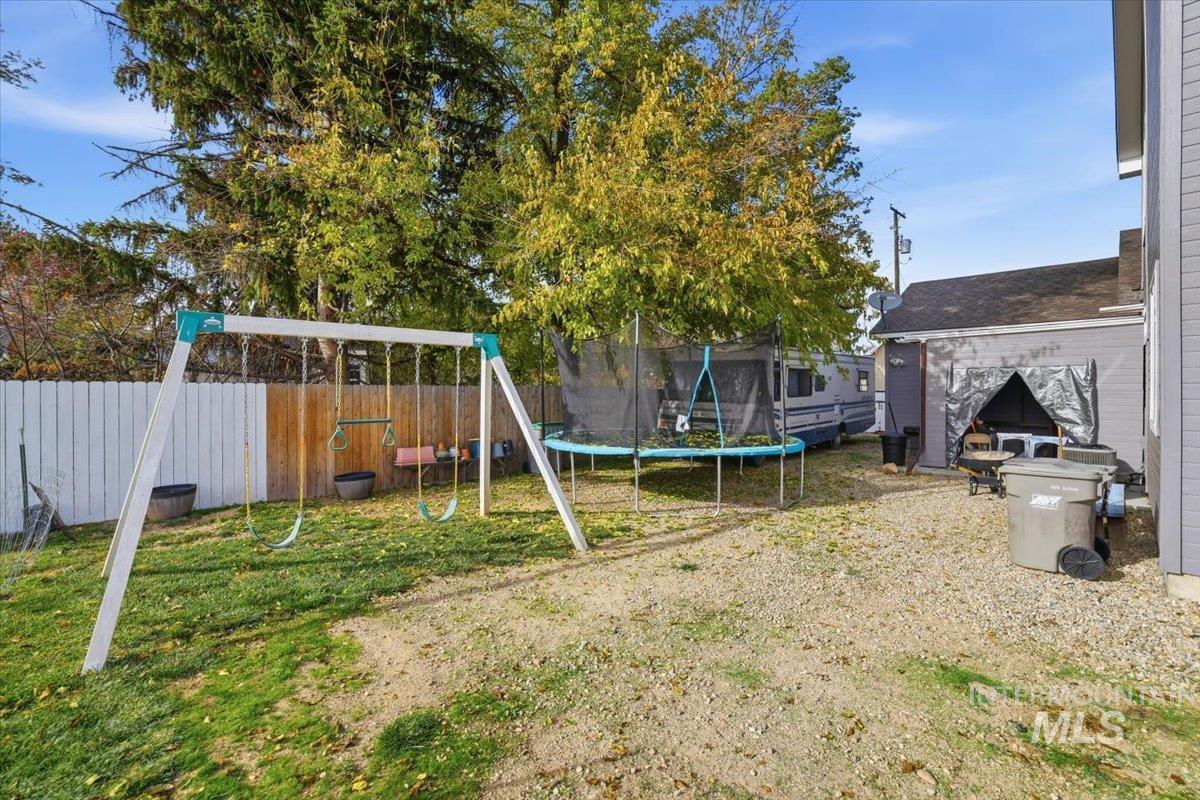 Fenced backyard featuring a playground and a trampoline