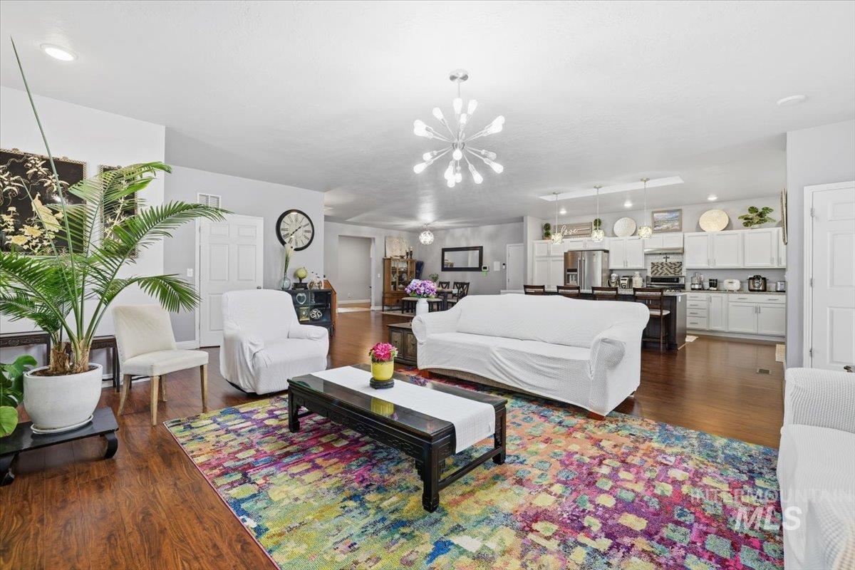 Living area with dark wood finished floors, a chandelier, and recessed lighting
