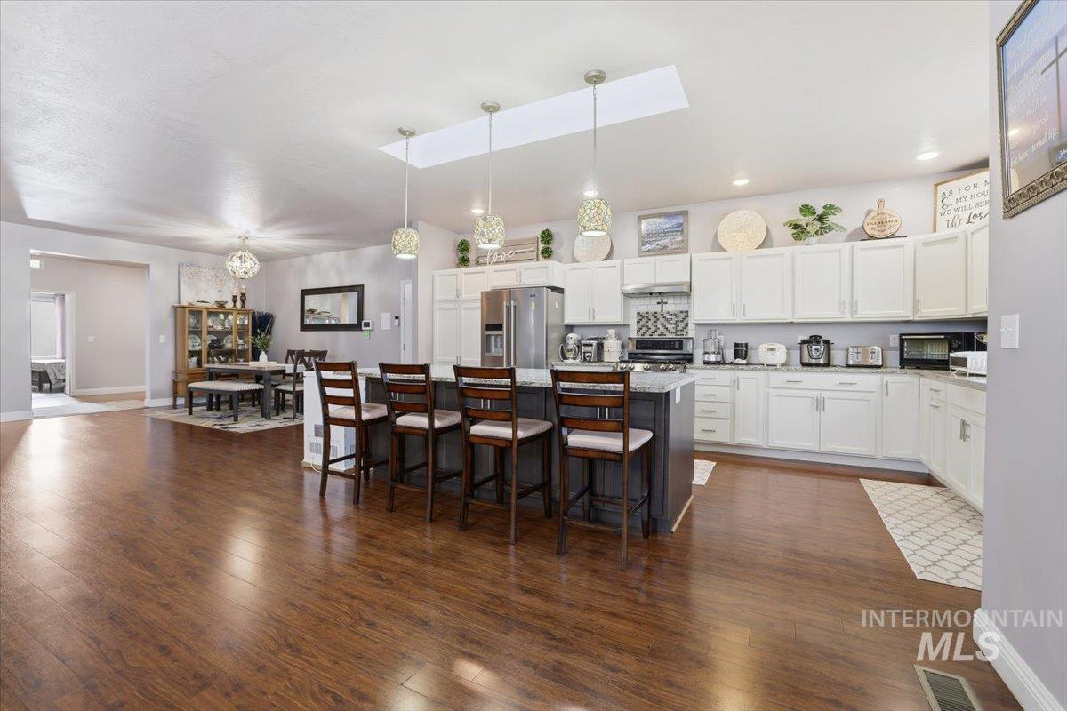 Kitchen featuring white cabinets, a skylight, pendant lighting, a breakfast bar area, and a kitchen island