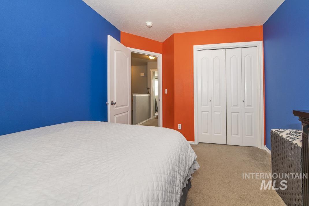 Bedroom with light colored carpet, a closet, and a textured ceiling