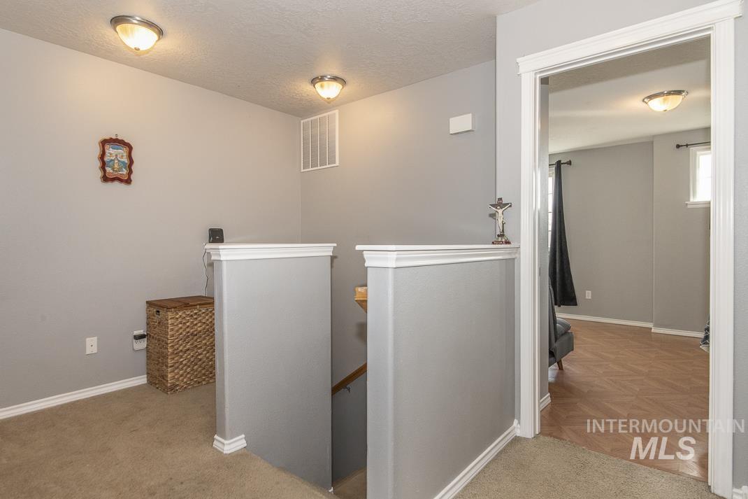 Corridor with an upstairs landing and a textured ceiling