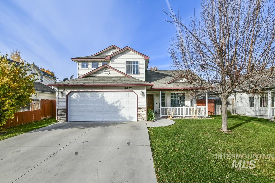 Traditional-style home featuring stone siding, covered porch, concrete driveway, an attached garage, and roof with shingles