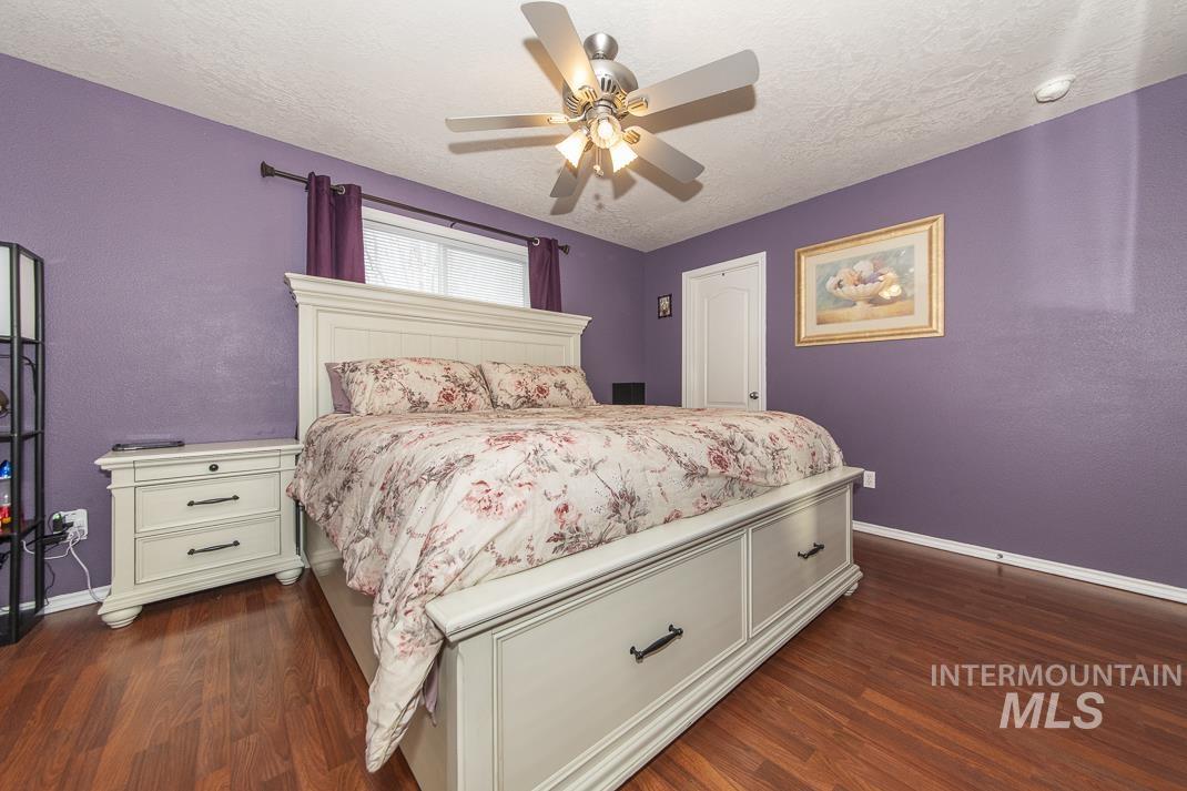Bedroom with dark wood finished floors, a textured ceiling, and a ceiling fan