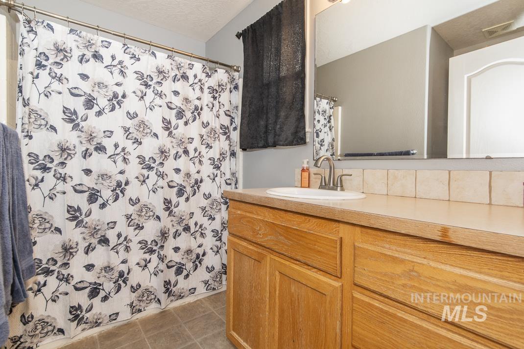 Full bathroom featuring curtained shower, vanity, light tile patterned floors, and a textured ceiling