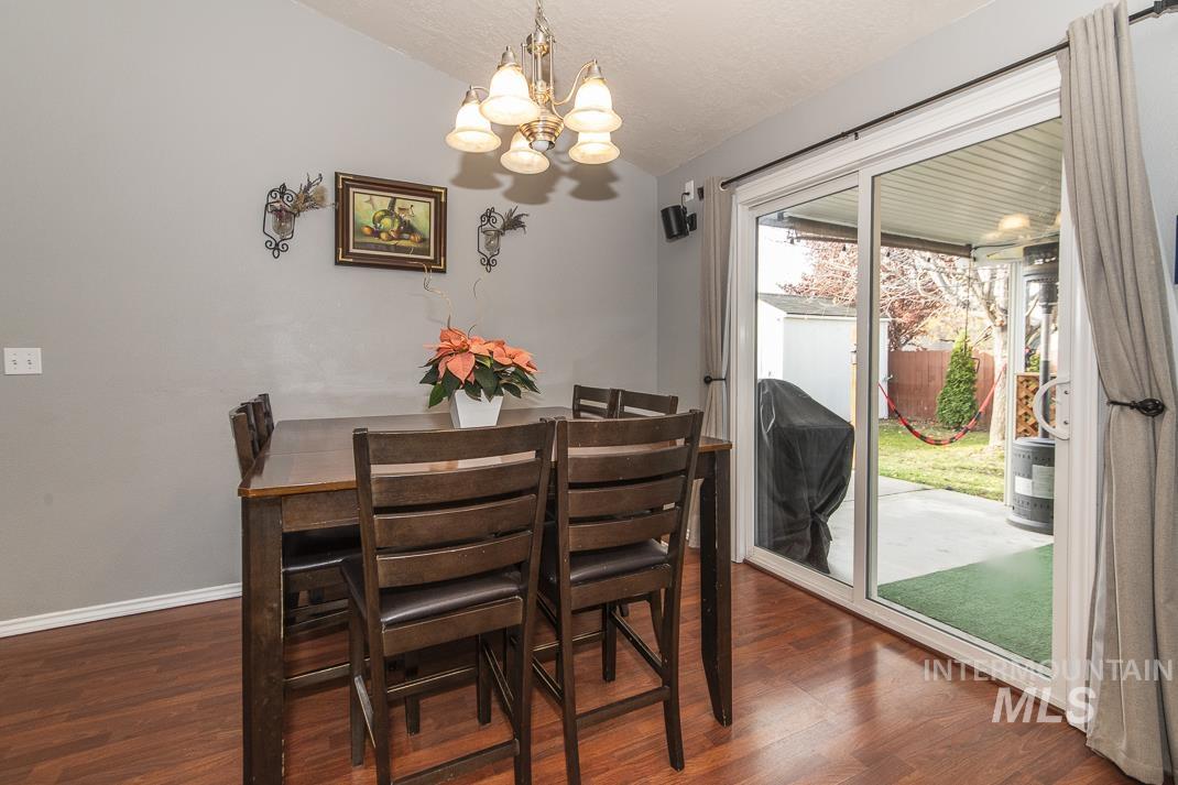 Dining area featuring vaulted ceiling, a chandelier, dark wood-type flooring, and a textured ceiling