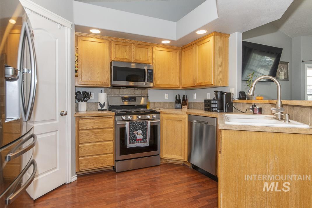 Kitchen featuring light countertops, appliances with stainless steel finishes, dark wood-type flooring, recessed lighting, and a peninsula