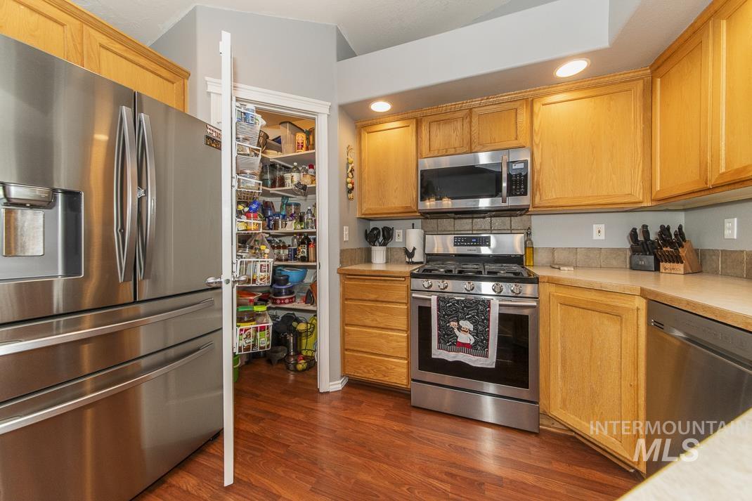Kitchen featuring appliances with stainless steel finishes, light countertops, dark wood-style flooring, and recessed lighting