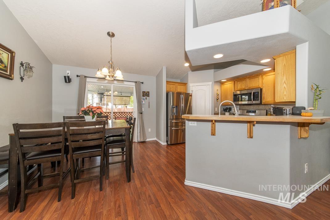 Kitchen featuring a peninsula, stainless steel appliances, a breakfast bar, dark wood-style floors, and a chandelier