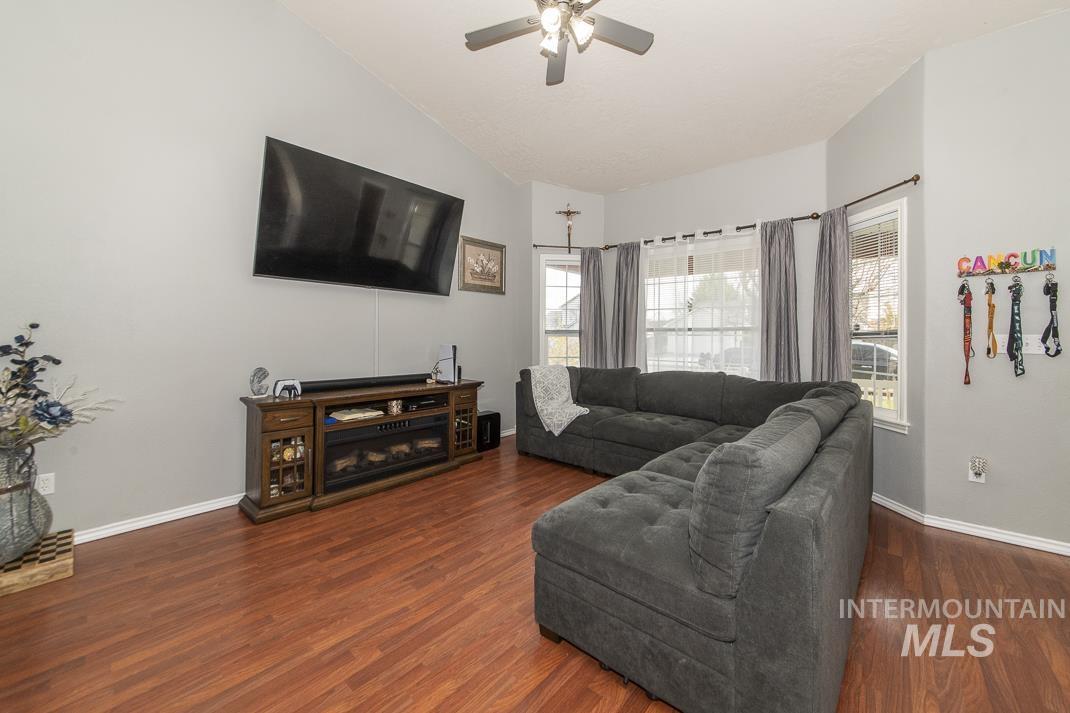 Living room with plenty of natural light, dark wood-type flooring, ceiling fan, and lofted ceiling