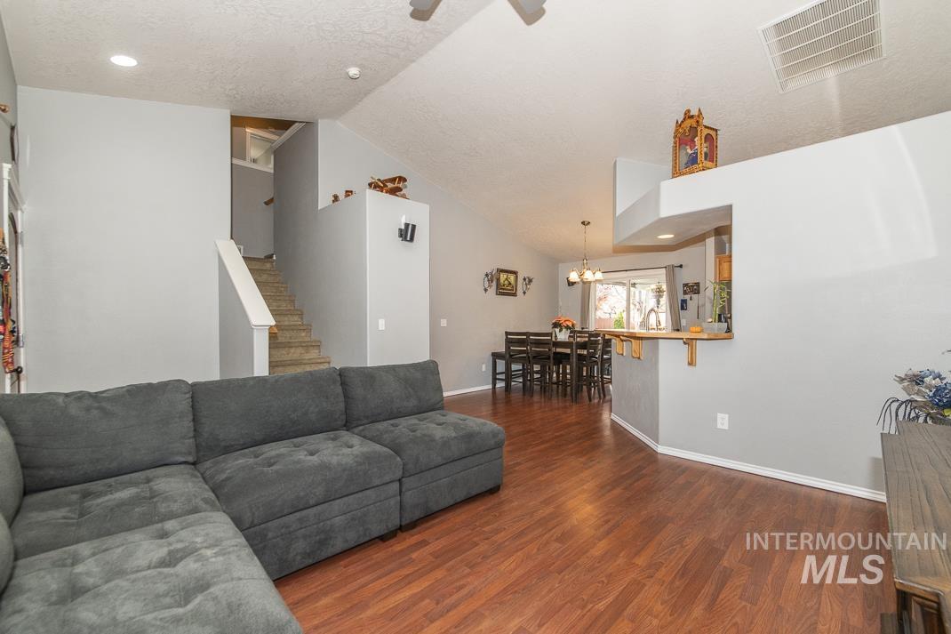 Living area with lofted ceiling, dark wood finished floors, a chandelier, recessed lighting, and a ceiling fan