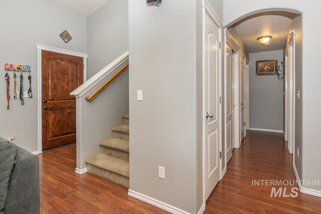 Hallway with arched walkways, dark wood-style floors, and stairs