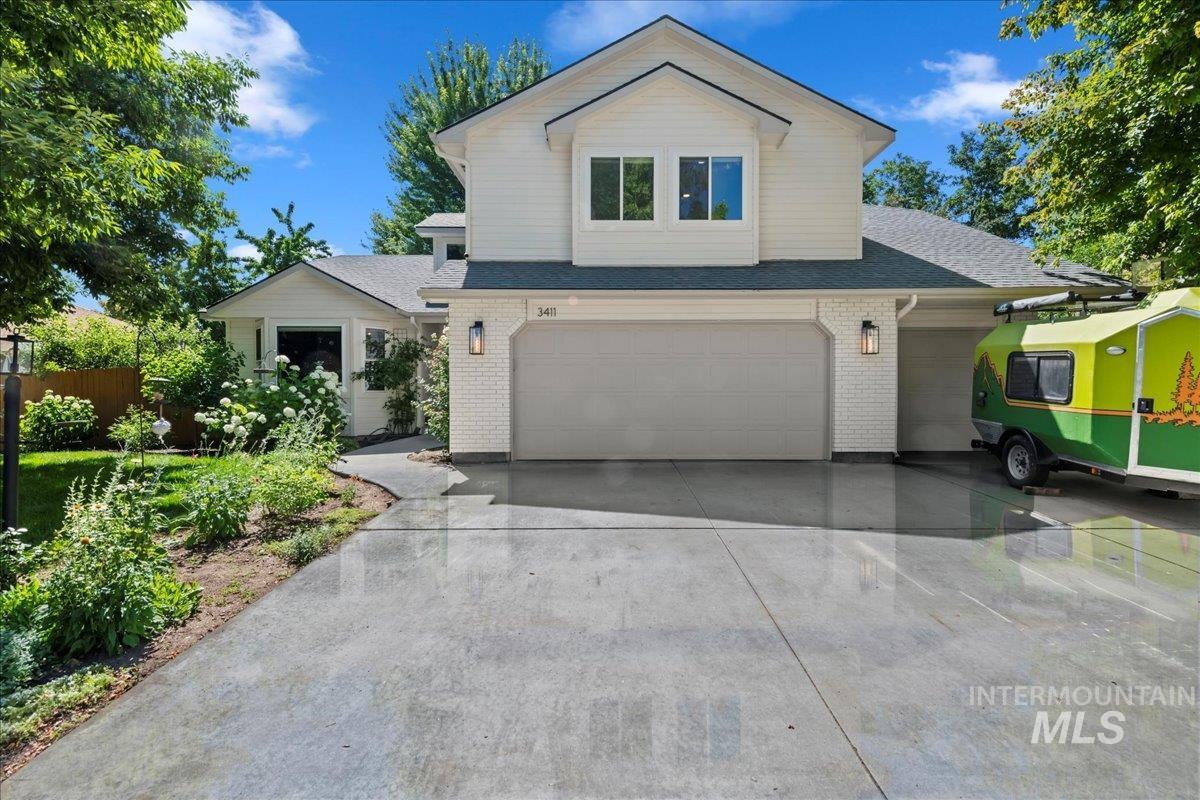 View of front facade with brick siding, concrete driveway, an attached garage, and roof with shingles