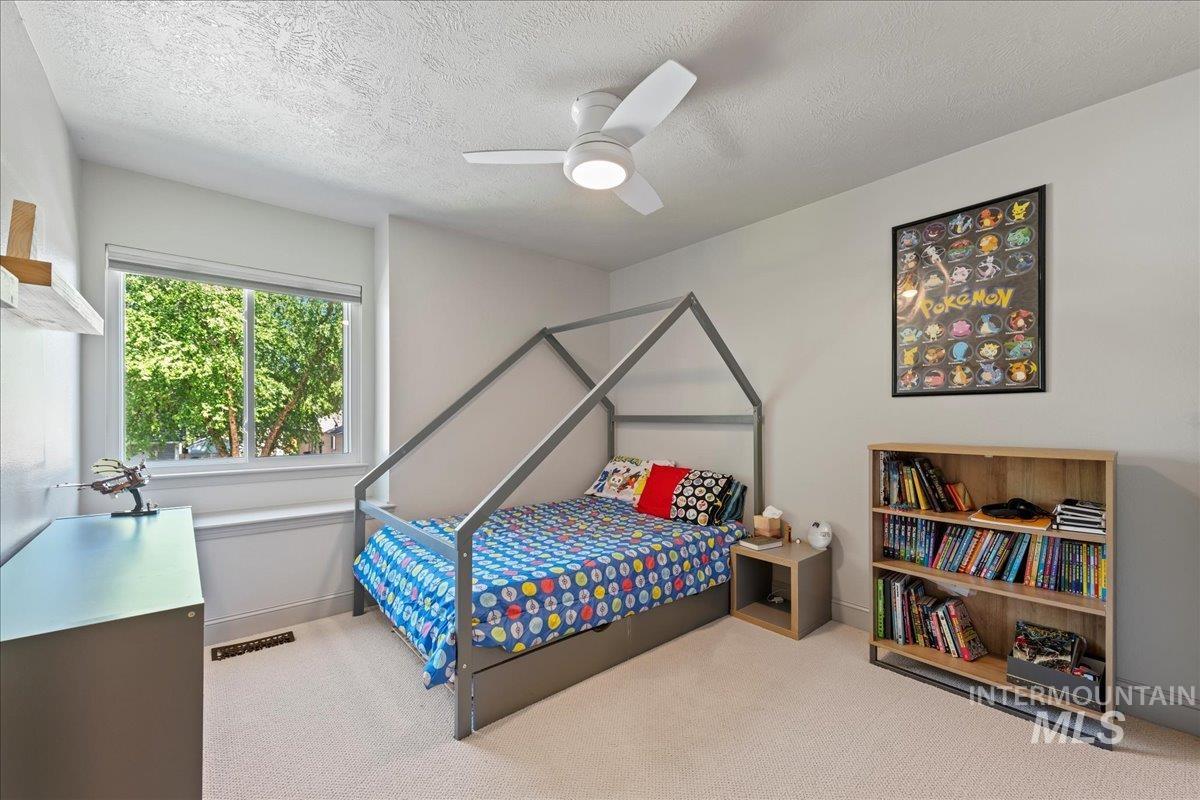 Carpeted bedroom with a textured ceiling and a ceiling fan