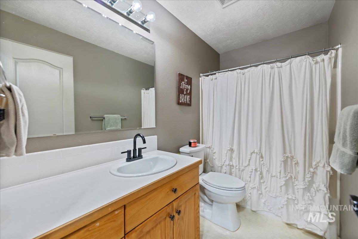 Full bath featuring vanity, a textured ceiling, and a shower with curtain