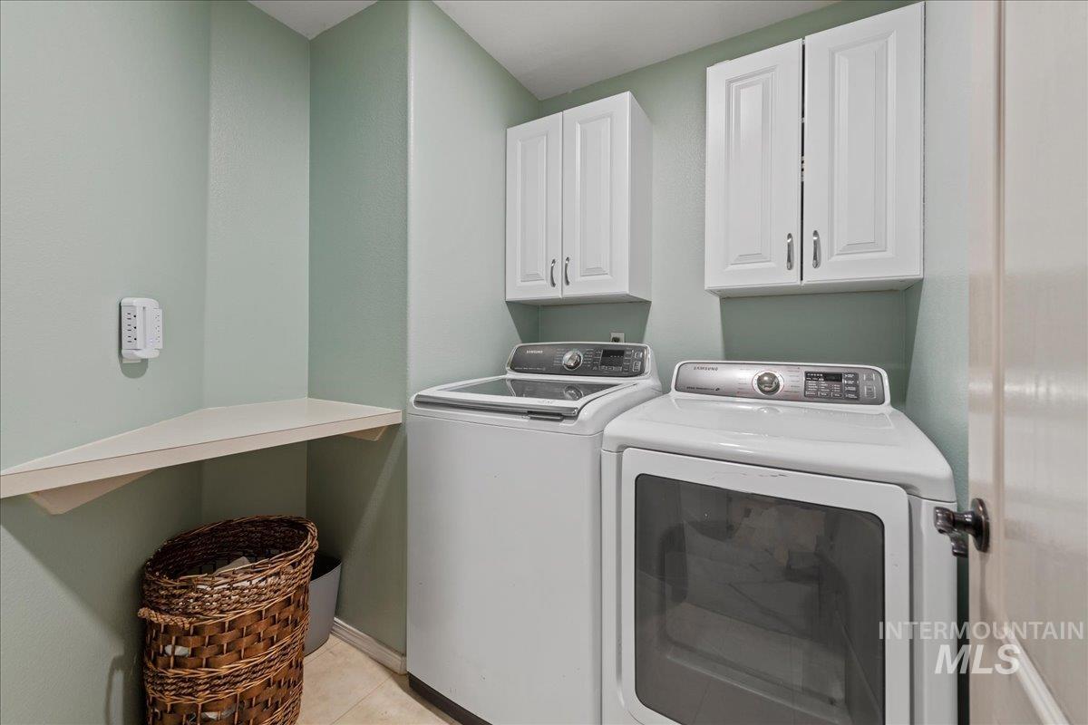 Laundry area with washing machine and clothes dryer, cabinet space, and light tile patterned floors