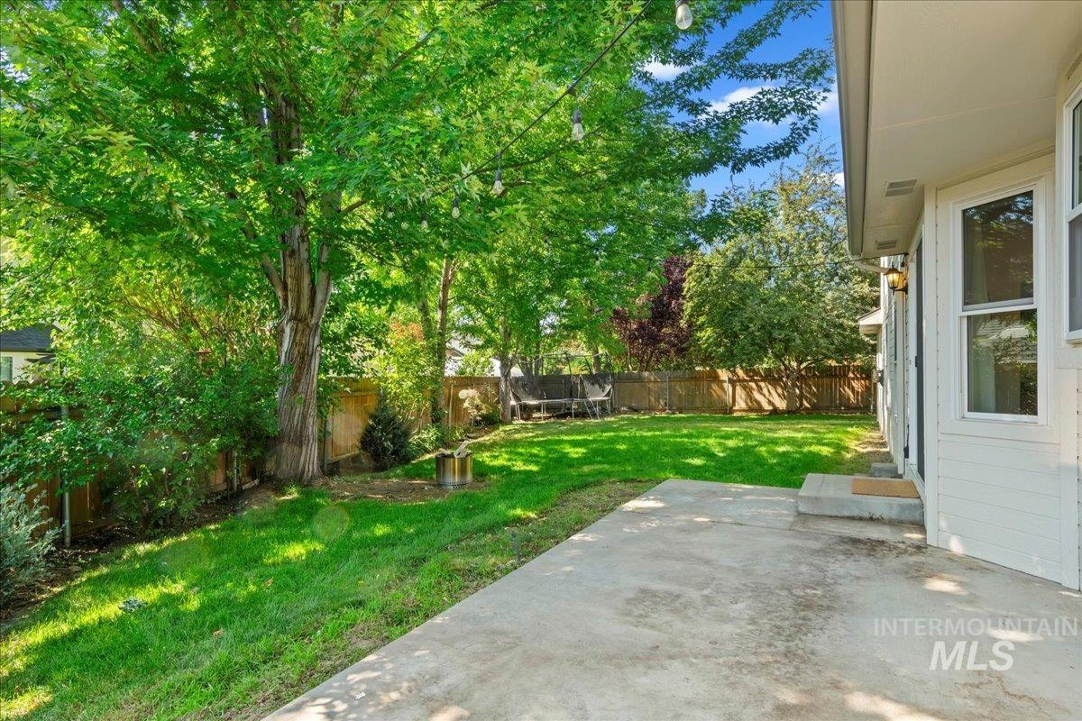 Fenced backyard with a trampoline and a patio