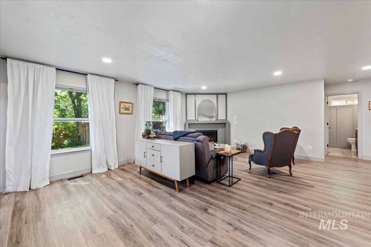 Living area featuring light wood-style floors, plenty of natural light, a fireplace, recessed lighting, and a textured ceiling
