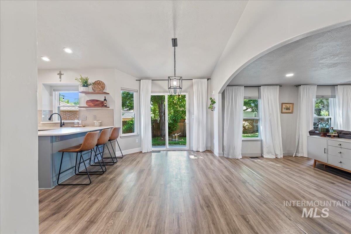 Dining area with wood finished floors, arched walkways, and recessed lighting