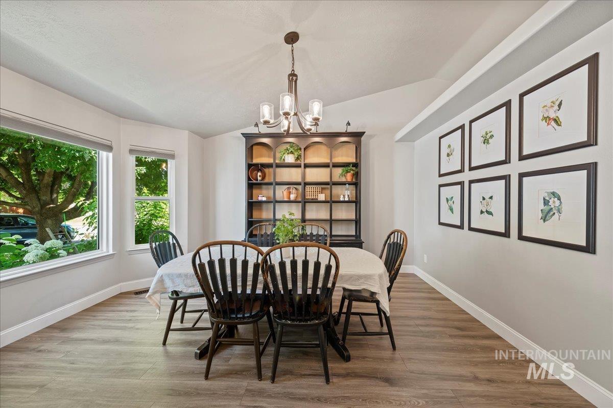 Dining room featuring a chandelier, vaulted ceiling, and wood finished floors