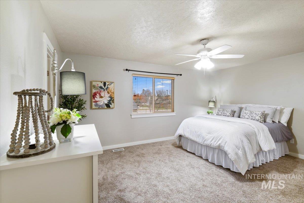 Bedroom with a textured ceiling, light carpet, and ceiling fan