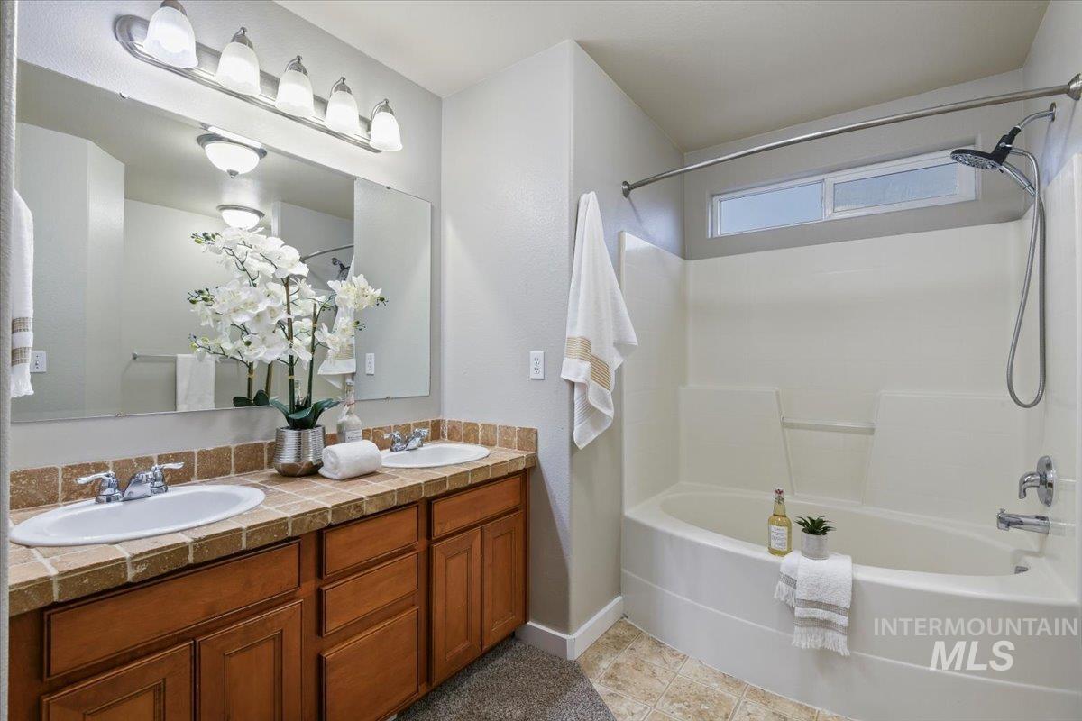 Full bathroom featuring double vanity, shower / bathtub combination, and light tile patterned floors