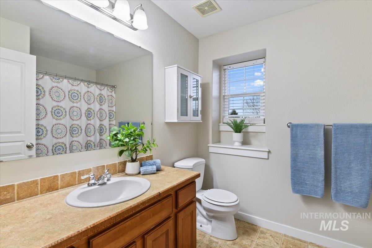 Full bathroom featuring a shower with shower curtain, vanity, and light tile patterned floors