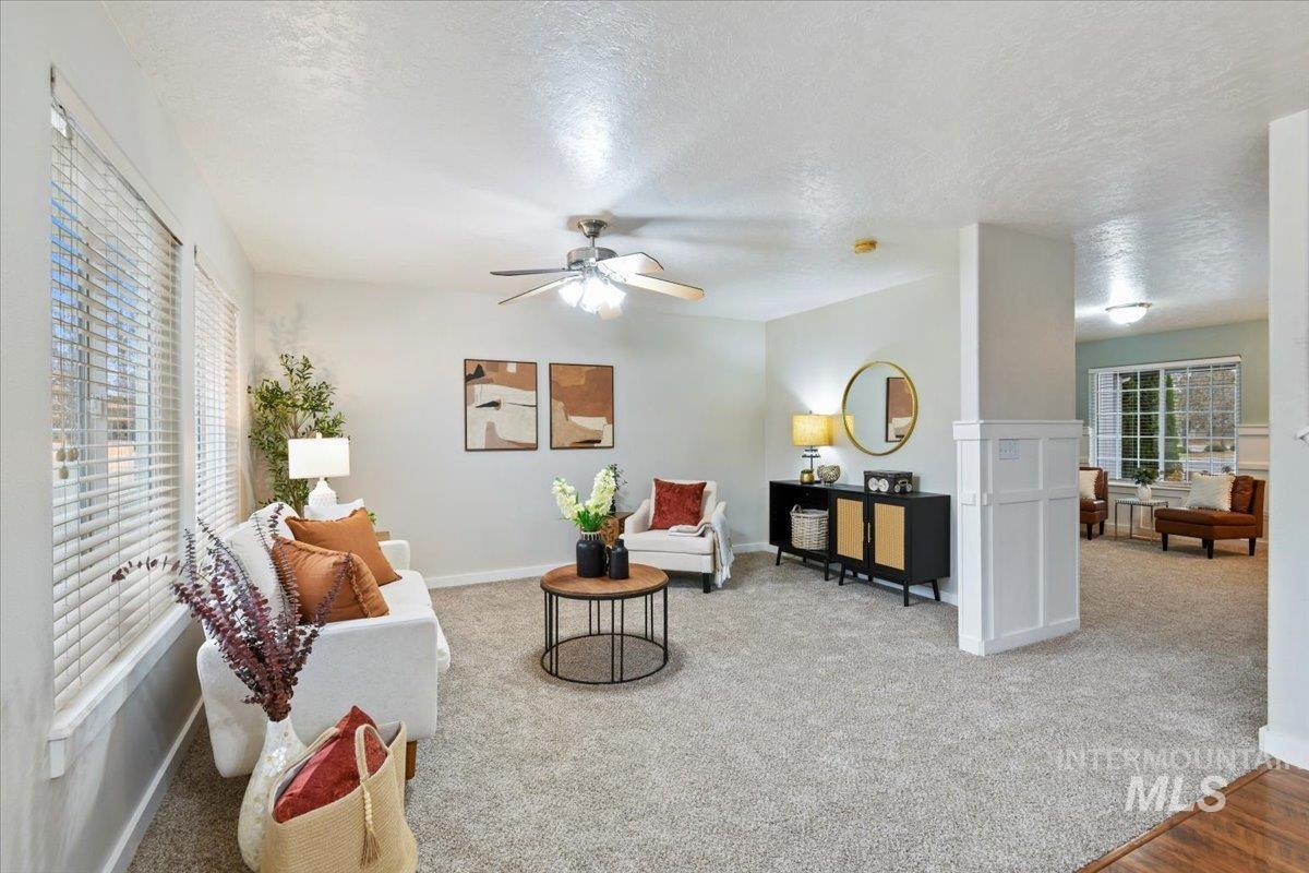 Living area featuring a textured ceiling, light colored carpet, and ceiling fan