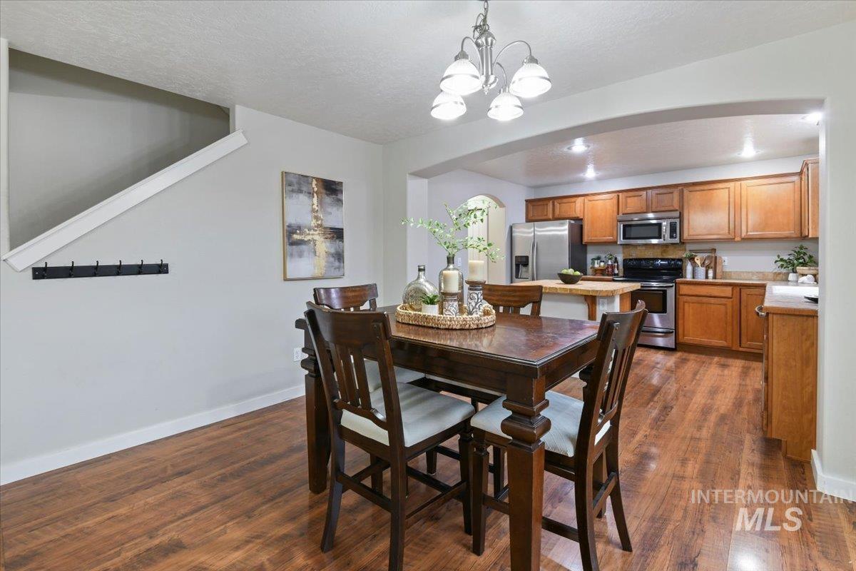 Dining room featuring dark wood-style floors, a chandelier, and a textured ceiling
