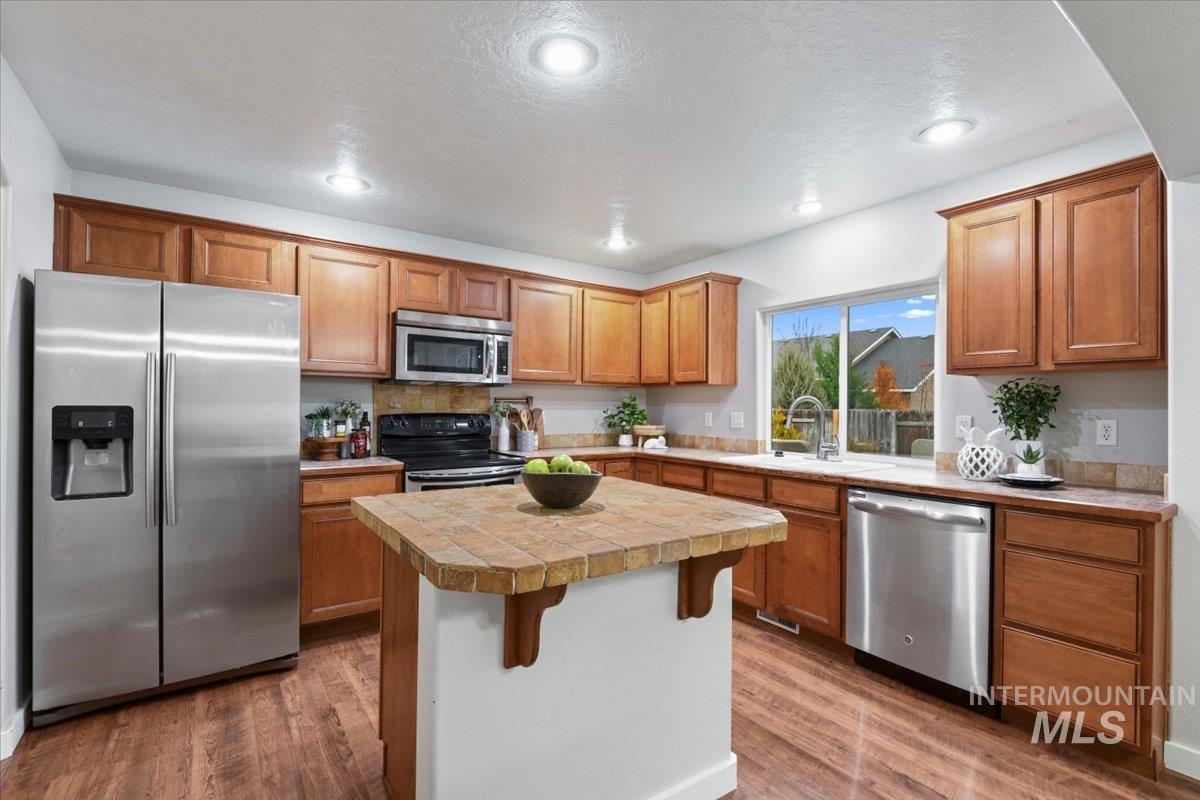 Kitchen with stainless steel appliances, brown cabinets, a kitchen bar, dark wood-style flooring, and recessed lighting