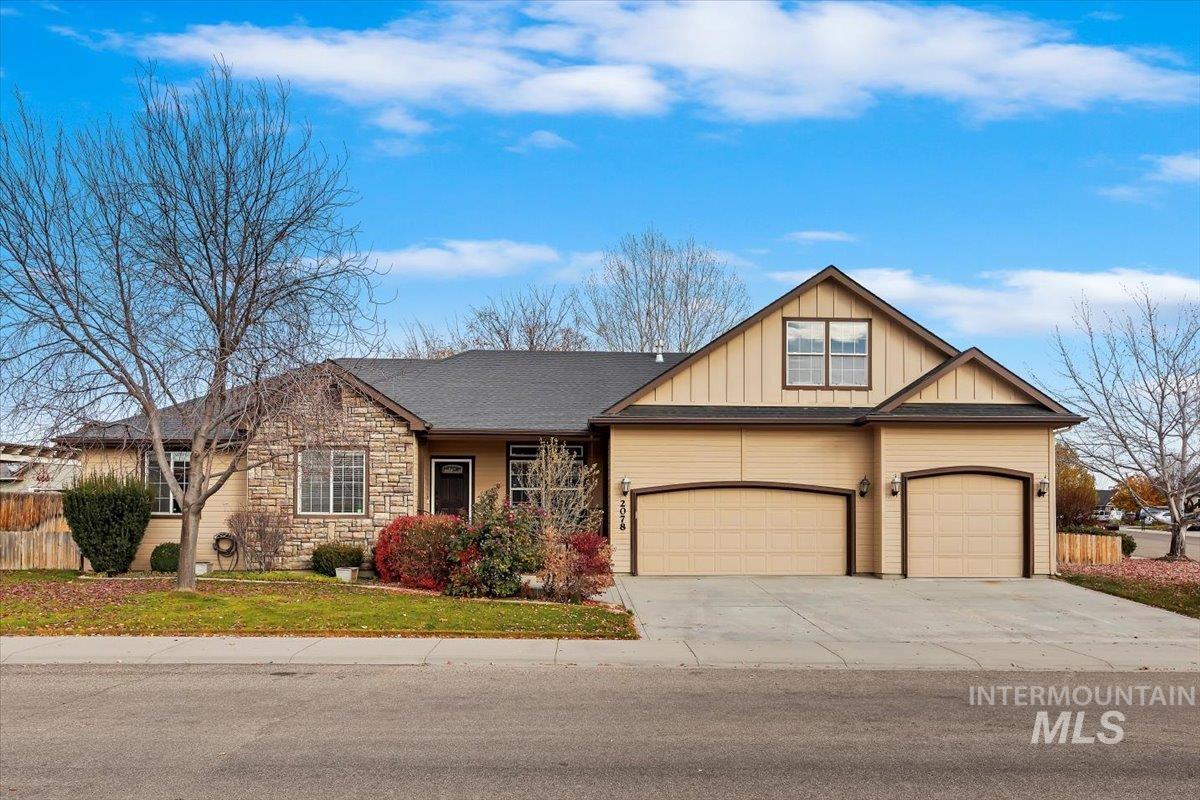 View of front facade with covered porch, concrete driveway, board and batten siding, stone siding, and roof with shingles