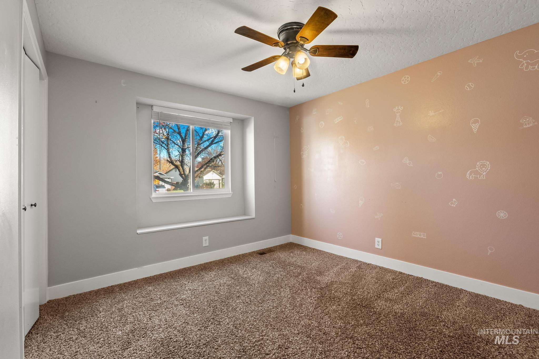 Spare room featuring carpet flooring, a textured ceiling, and ceiling fan