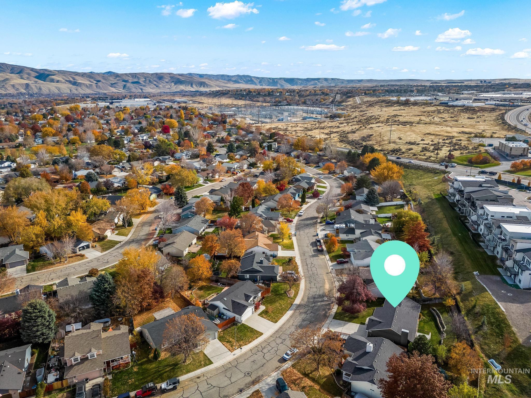 Aerial view of property and surrounding area with nearby suburban area and a mountainous background