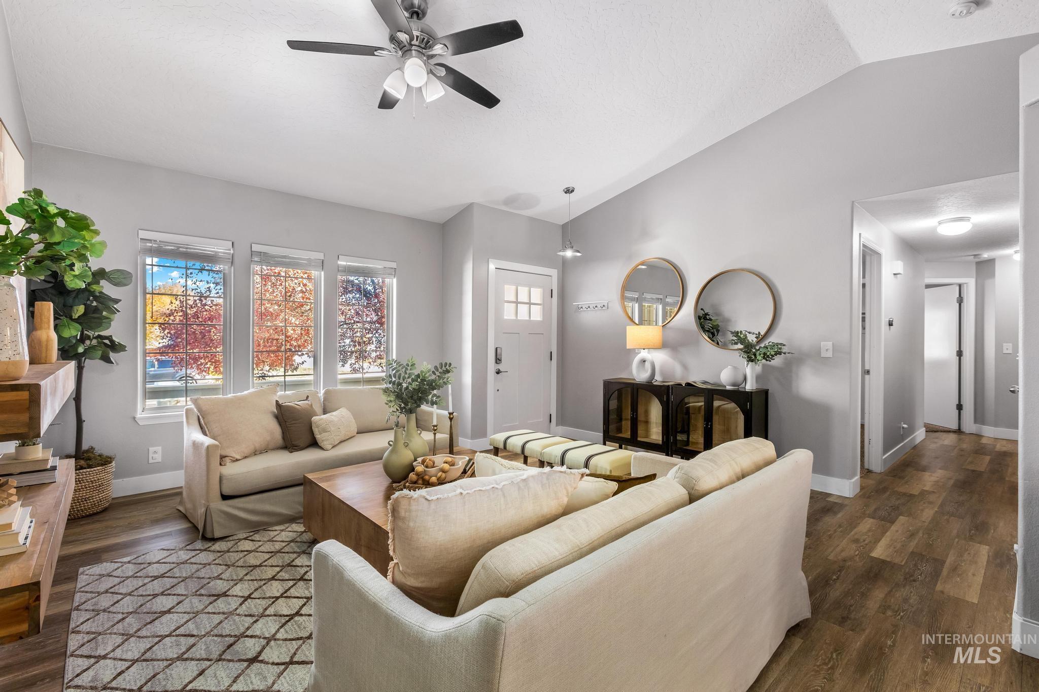 Living area with vaulted ceiling, ceiling fan, and dark wood-style flooring