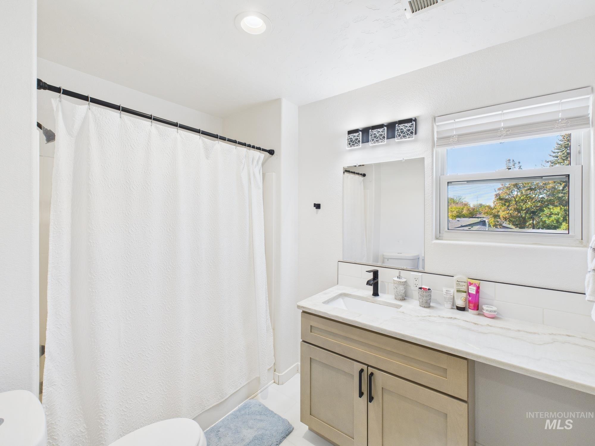 Bathroom featuring vanity and shower / bath combination with curtain