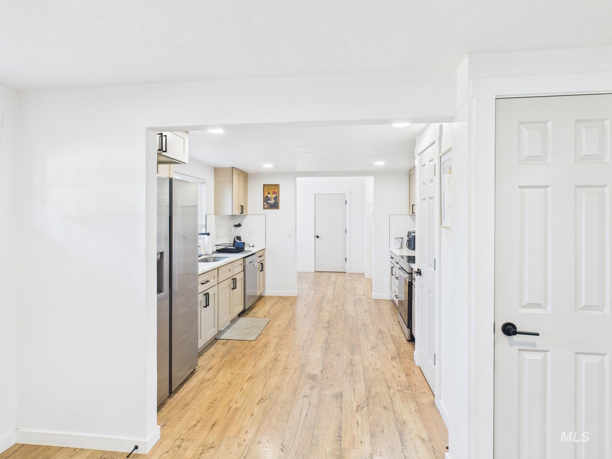 Kitchen featuring light countertops, light wood-style floors, stainless steel appliances, recessed lighting, and white cabinets