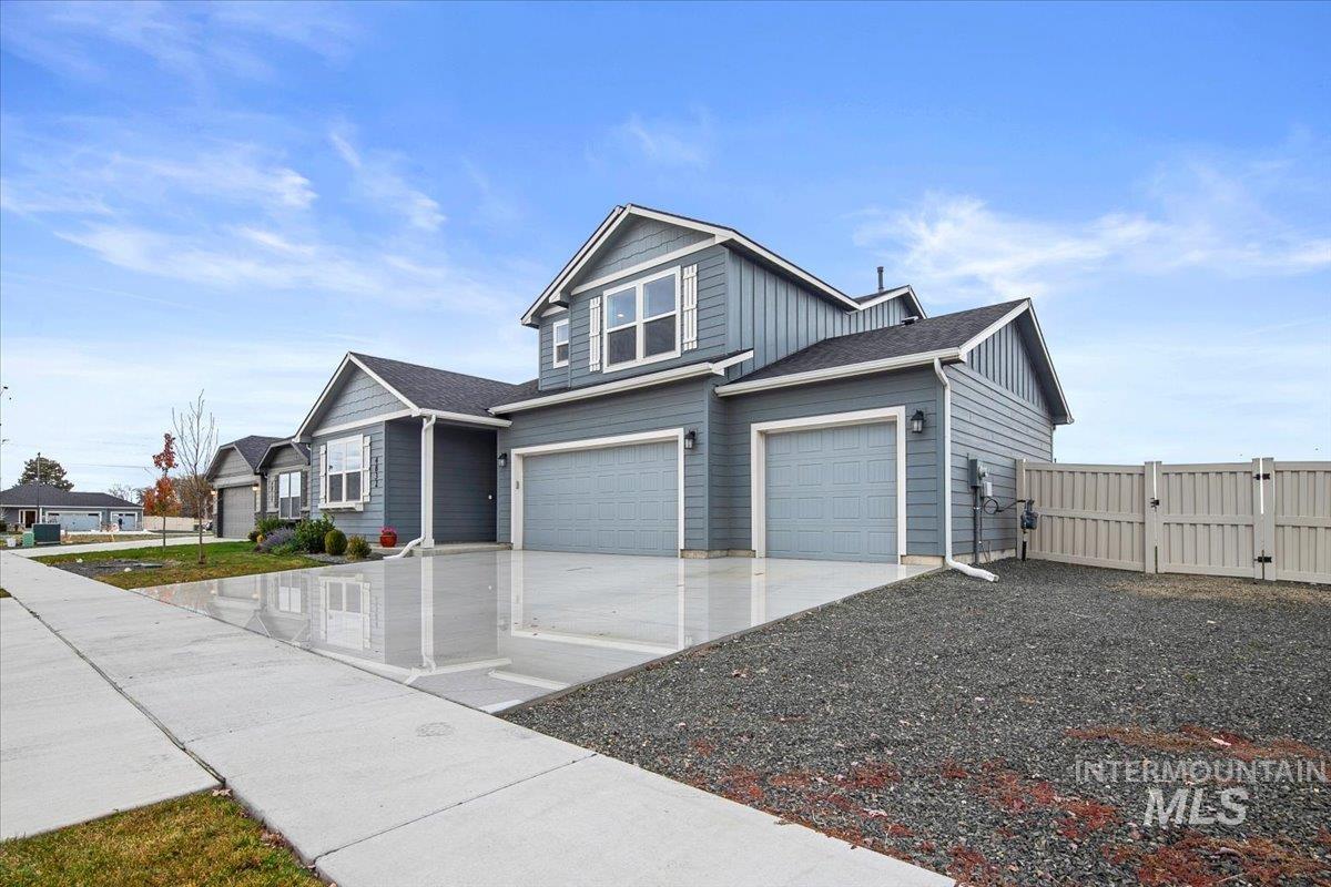 View of front of property with board and batten siding, concrete driveway, a garage, a gate, and roof with shingles
