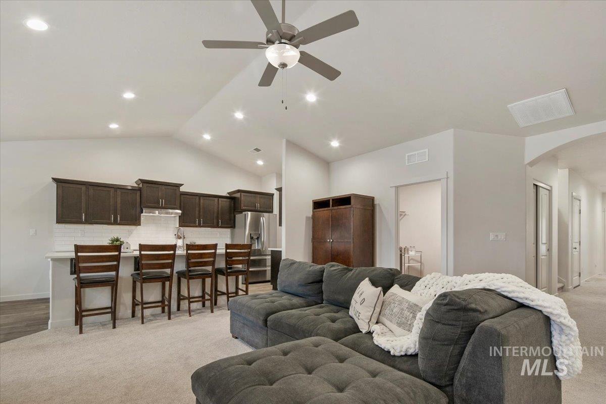 Living room featuring light carpet, lofted ceiling, arched walkways, ceiling fan, and recessed lighting