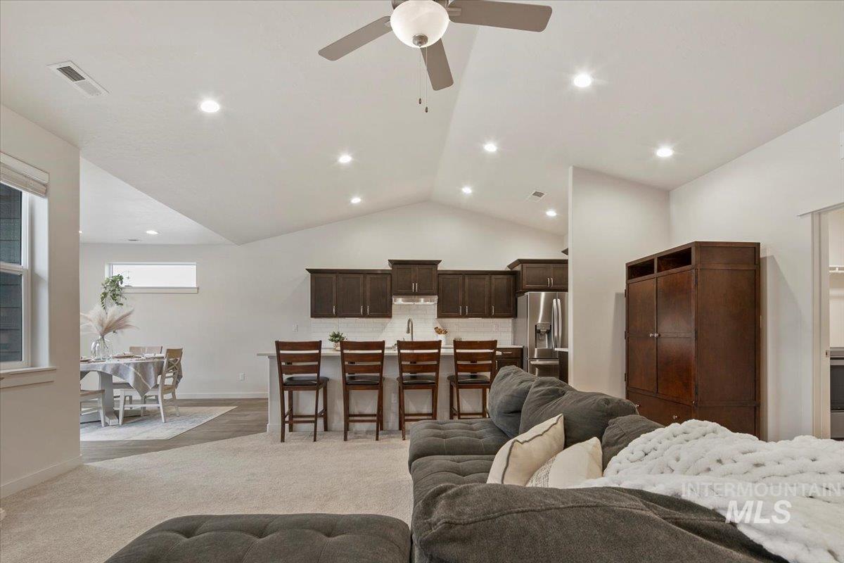Living area with vaulted ceiling, light colored carpet, ceiling fan, and recessed lighting