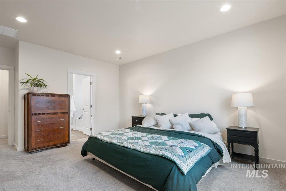 Bedroom featuring light colored carpet, recessed lighting, and ensuite bath